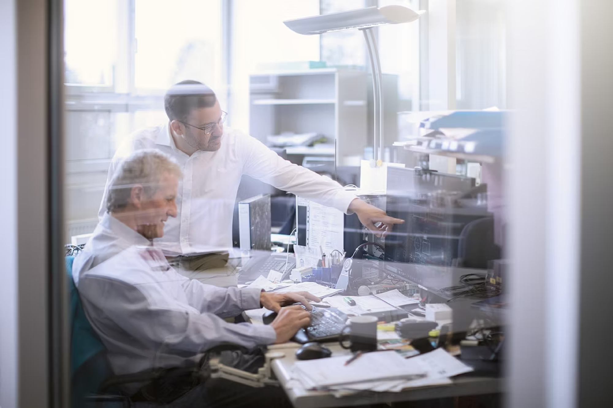 Zwei Personen unterhalten sich hinter einer Glasfront