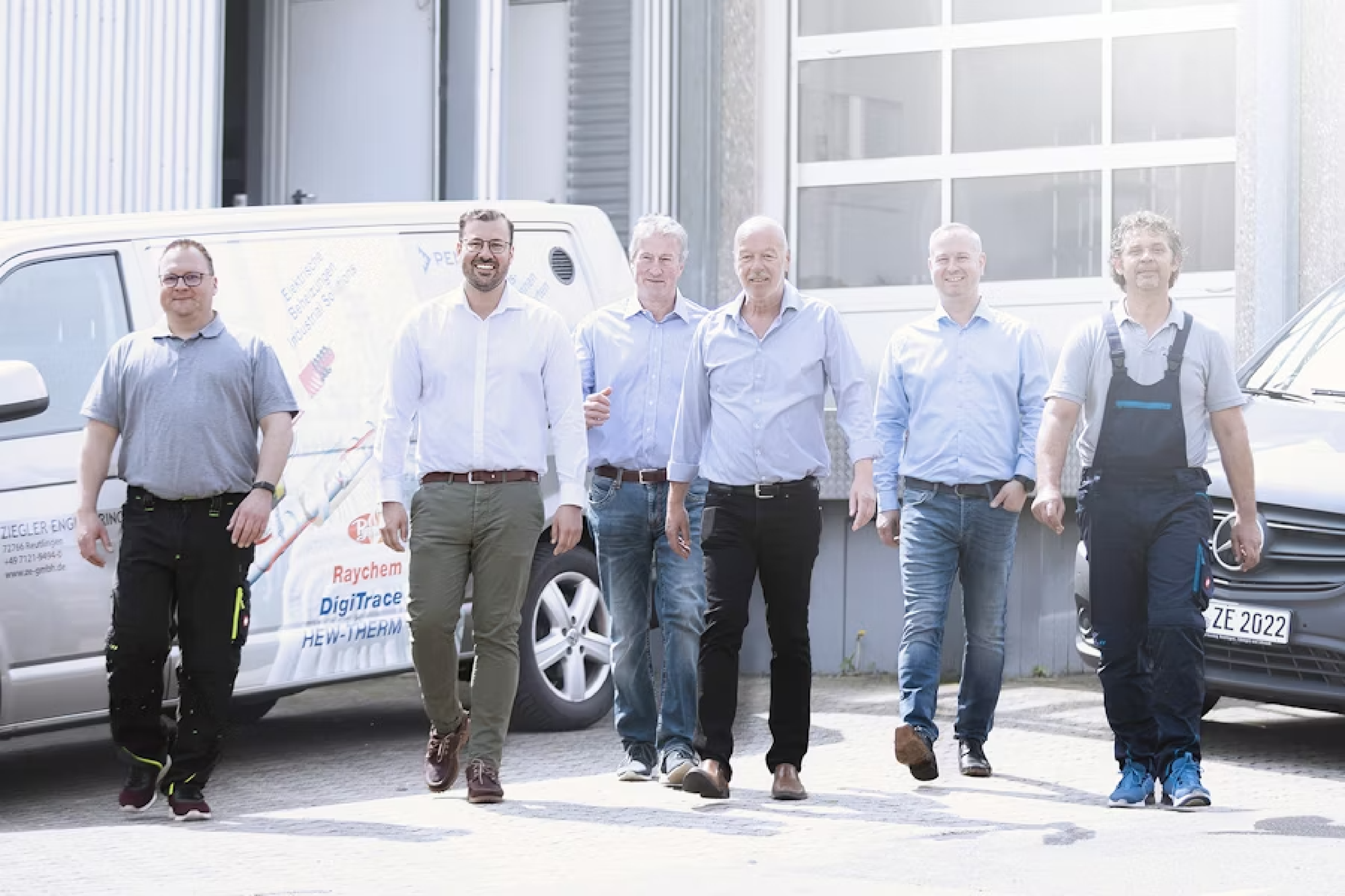 Das Team von Ziegler Engineering läuft auf einem Parkplatz der Kamera entgegen